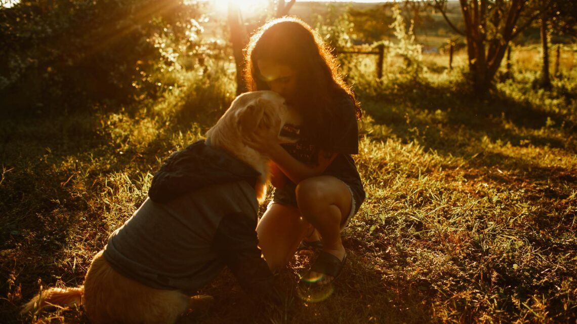 woman kissing dog in field