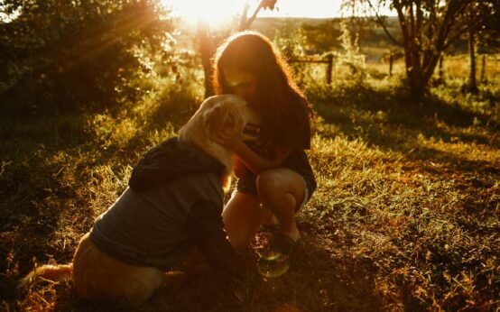 woman kissing dog in field