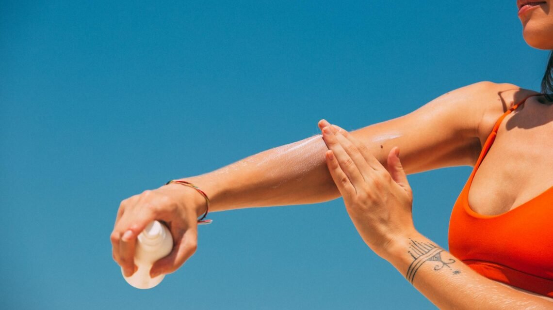 a woman applying sunscreen on arm