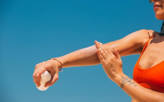 a woman applying sunscreen on arm