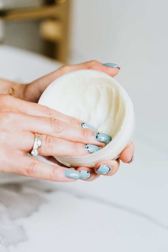 fingers on white round container with cream