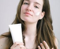 young woman presenting cosmetic product with white swear on face